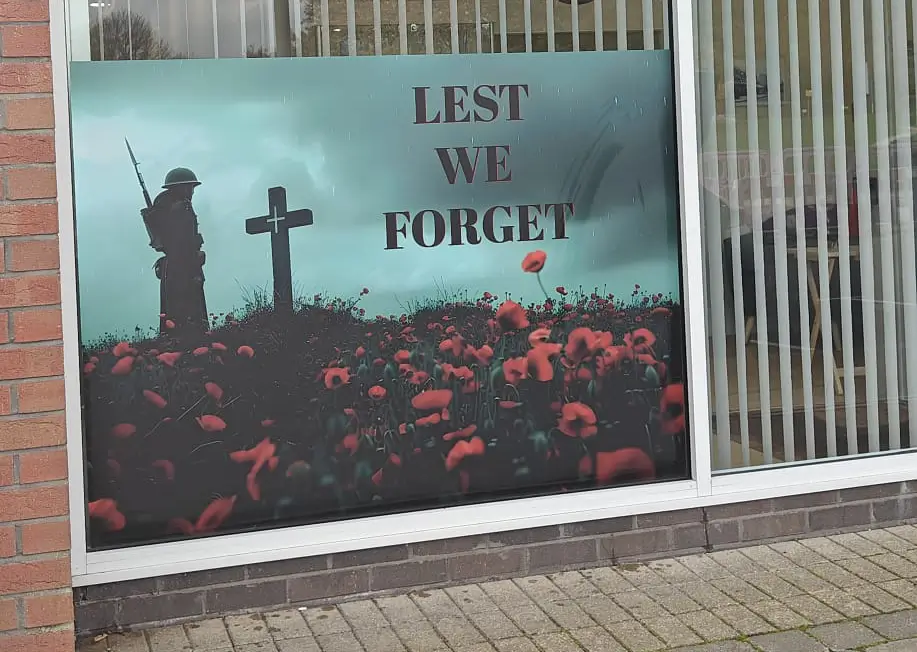 Lest We Forget poster with soldier, cross and poppies