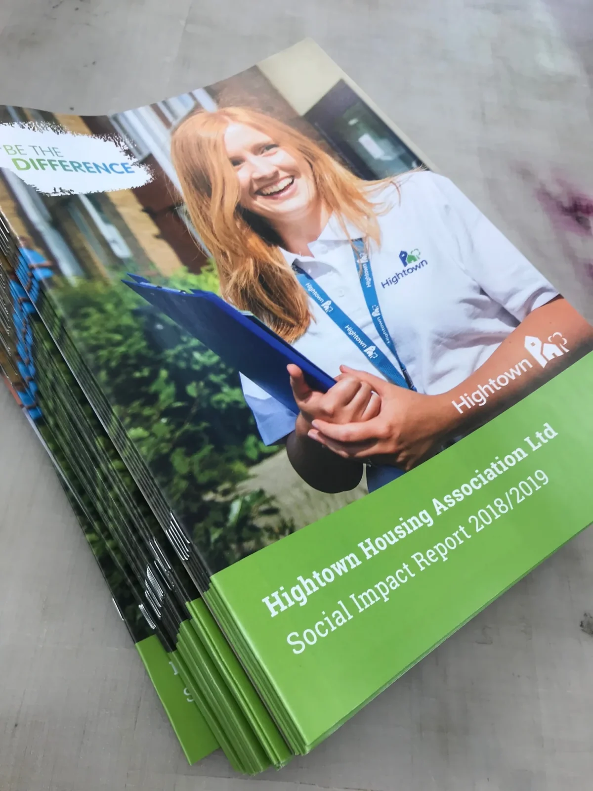 Stack of Hightown social impact reports featuring smiling employee