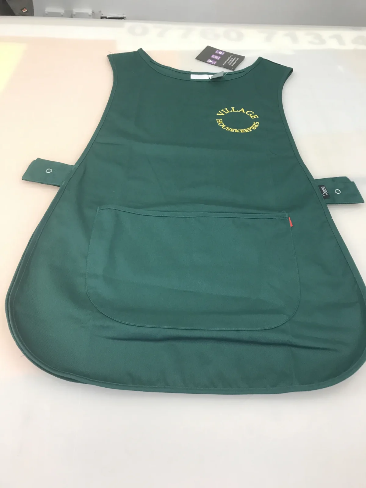Dark green Village Housekeepers tabard with large front pocket