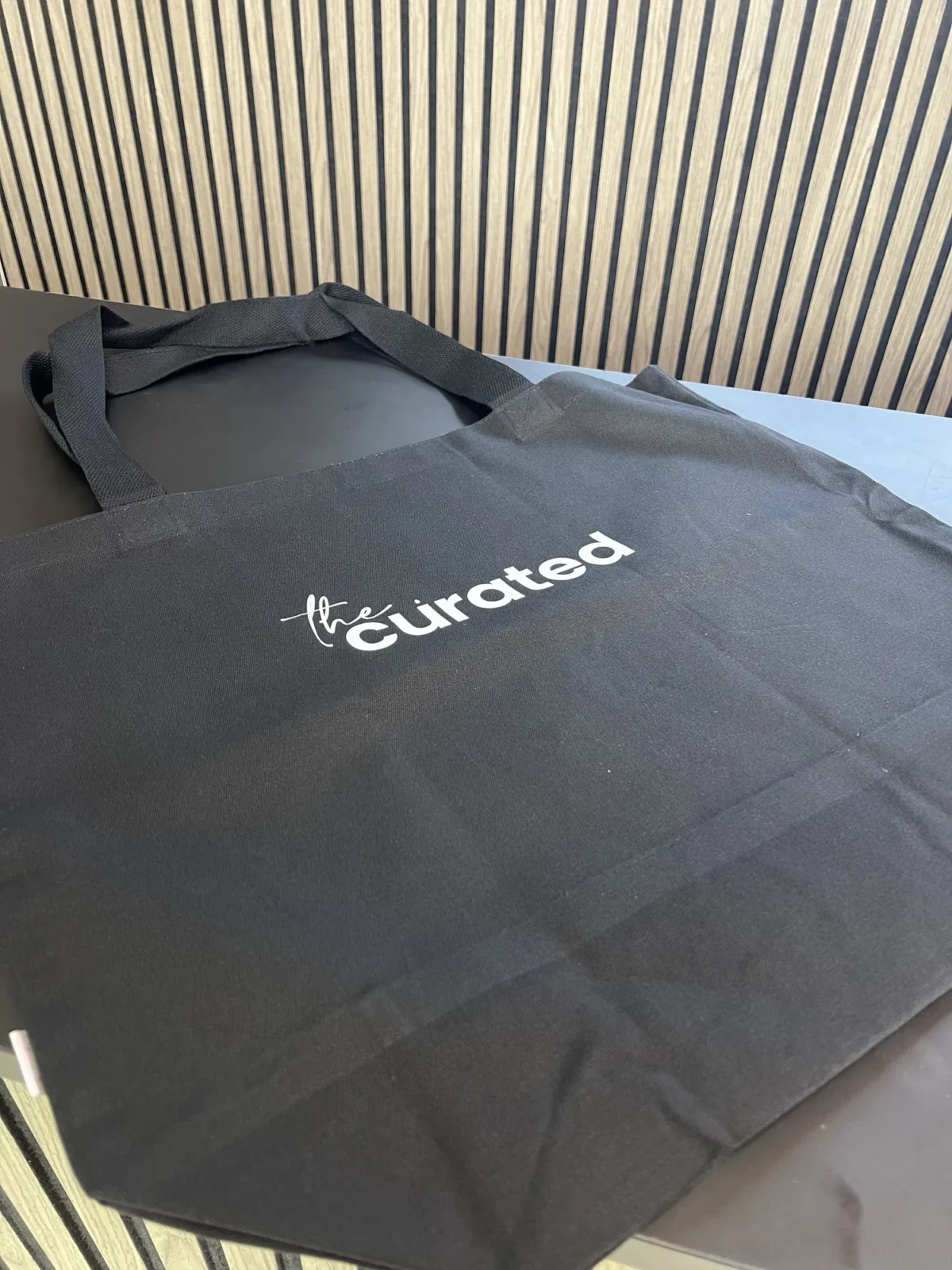 Black tote bag with The Curated logo