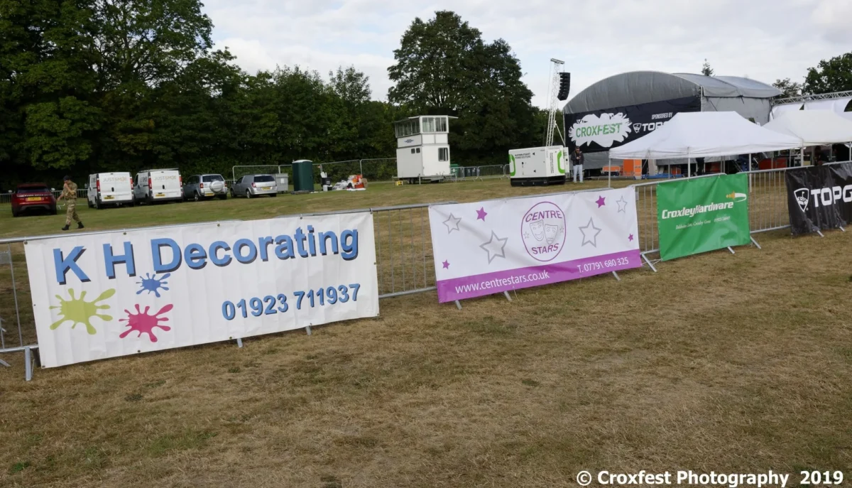 Sponsor banners beside outdoor festival stage and tents