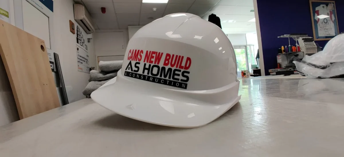 AS Homes branded white construction hard hat on table