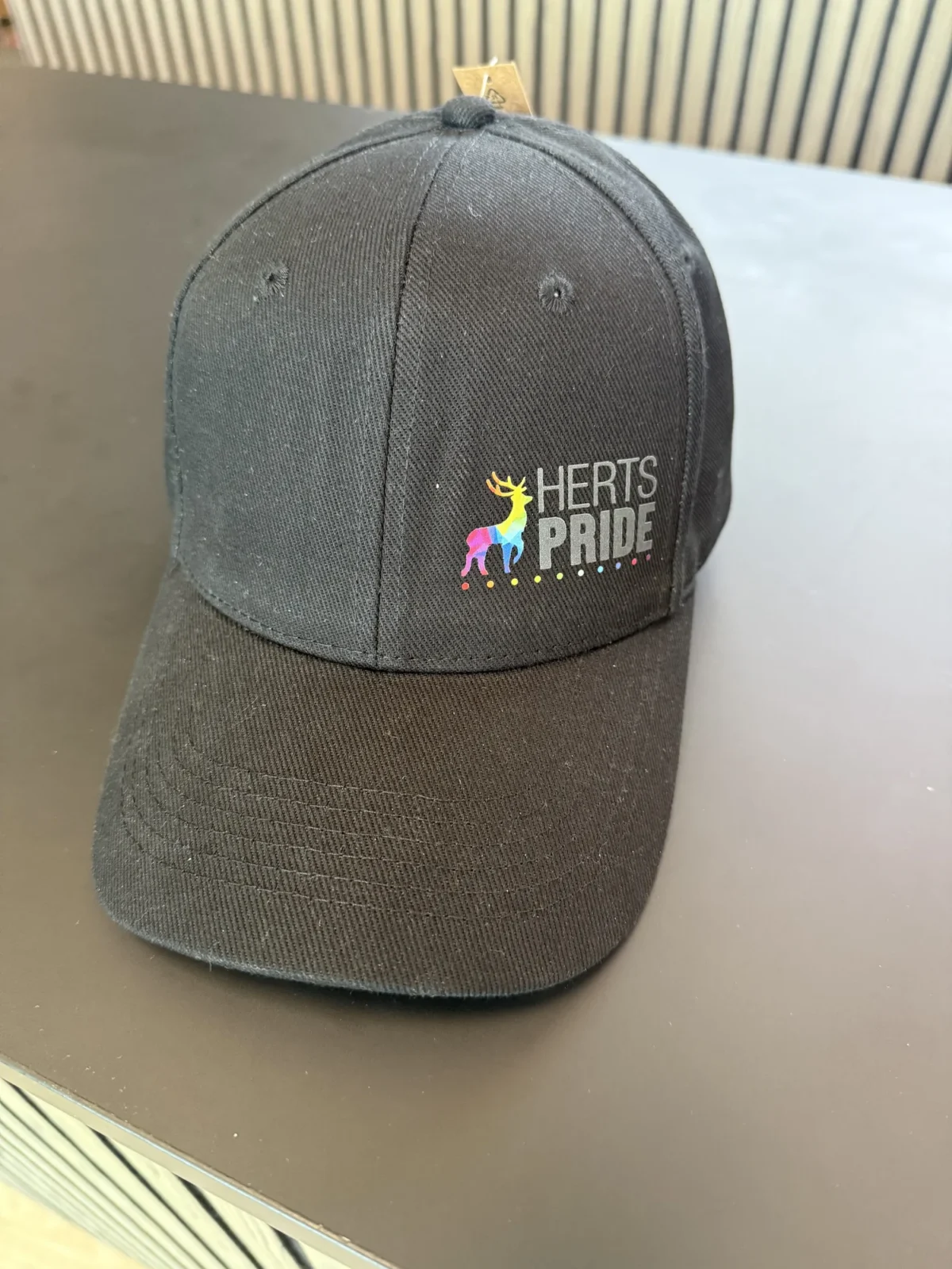 Black Herts Pride baseball cap with colourful deer logo