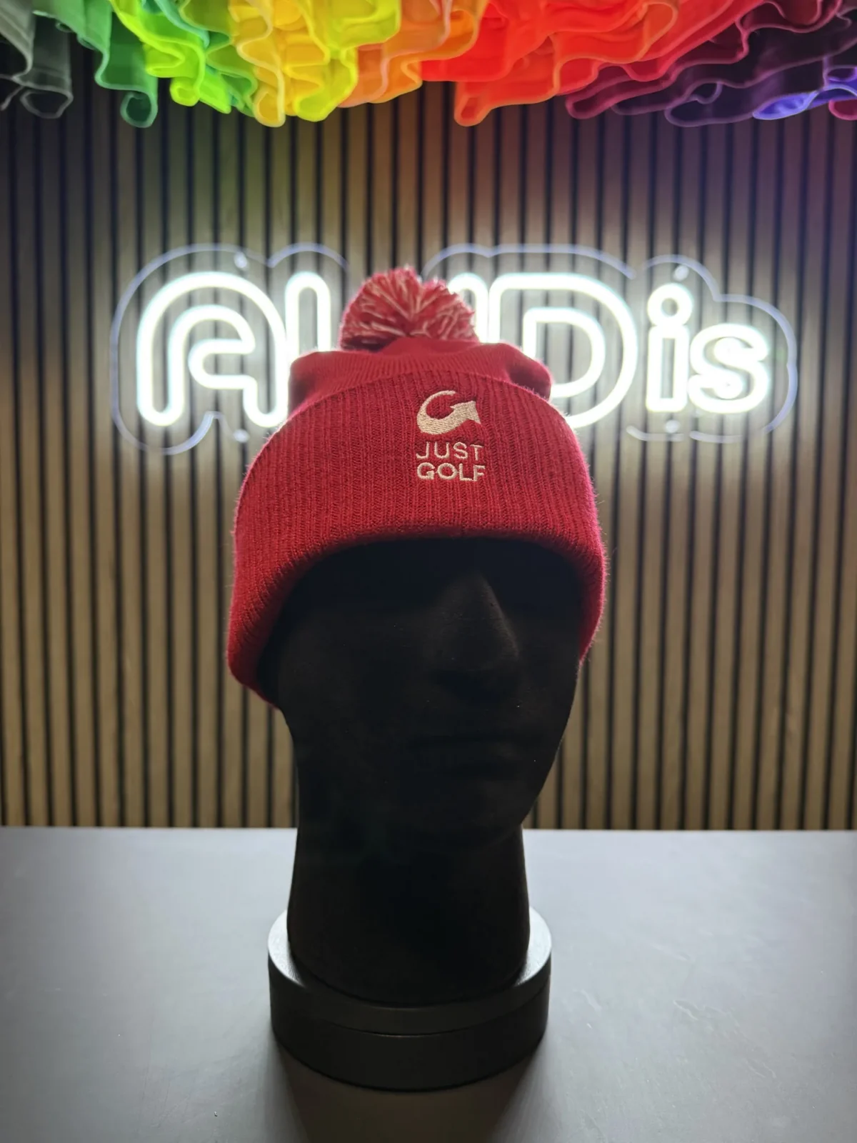 Red Just Golf pom-pom beanie on display mannequin