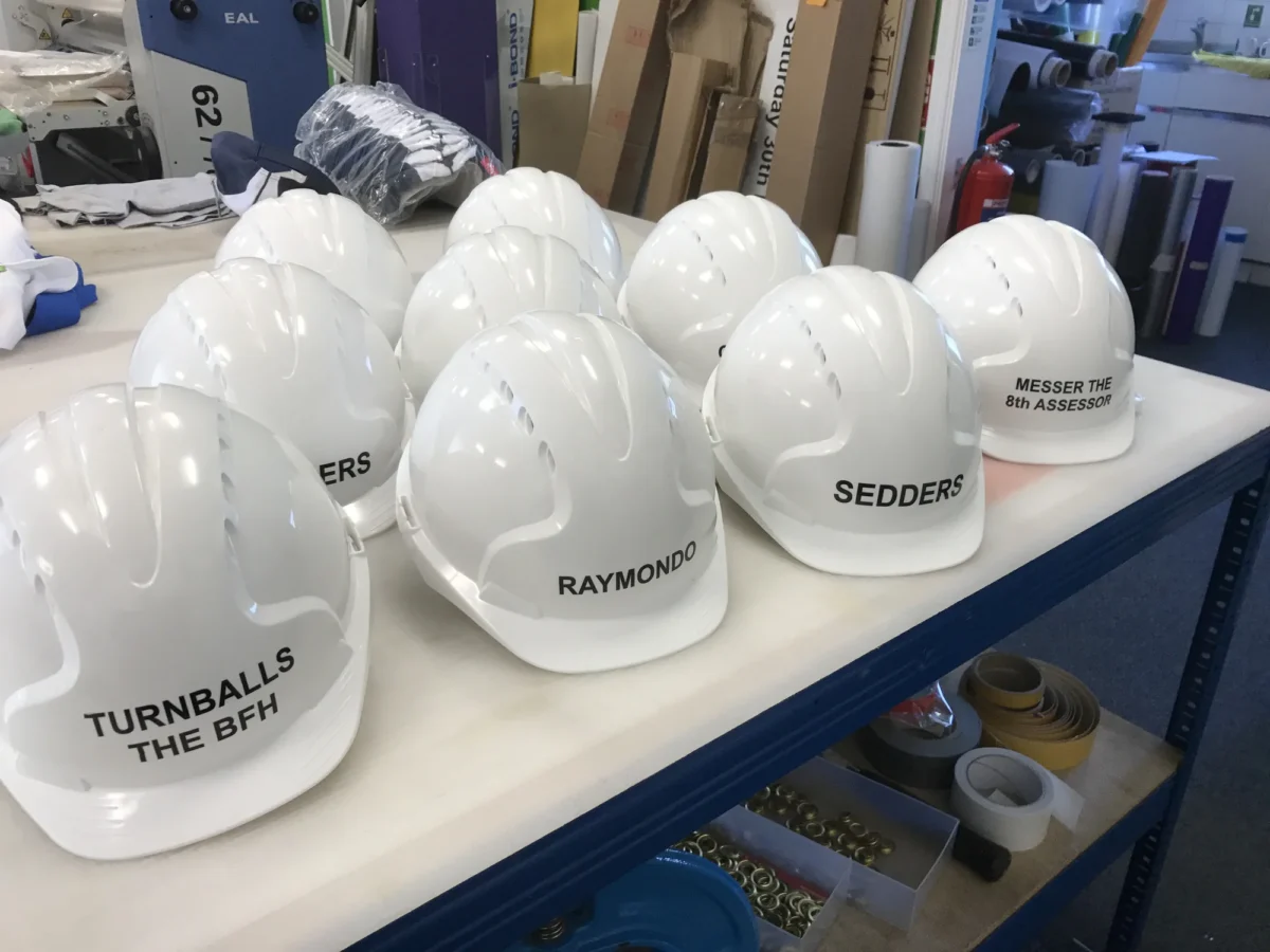 Personalised white safety helmets on a workshop table