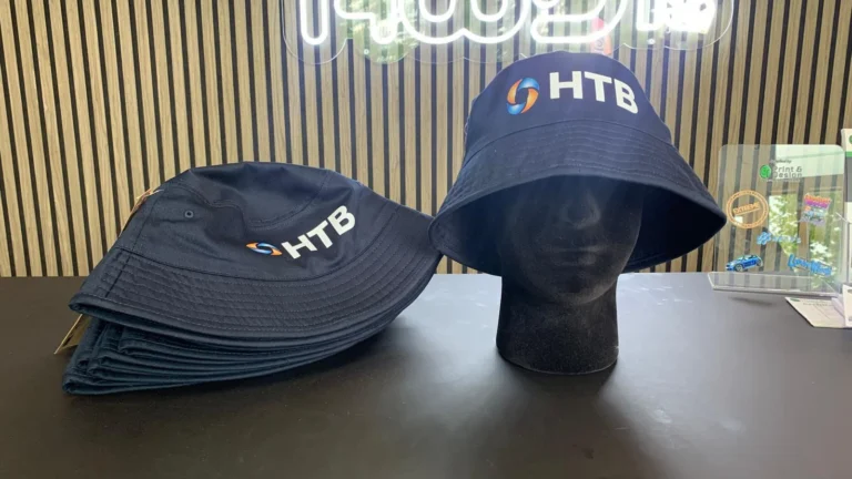 Black HTB-branded bucket hats displayed on a table
