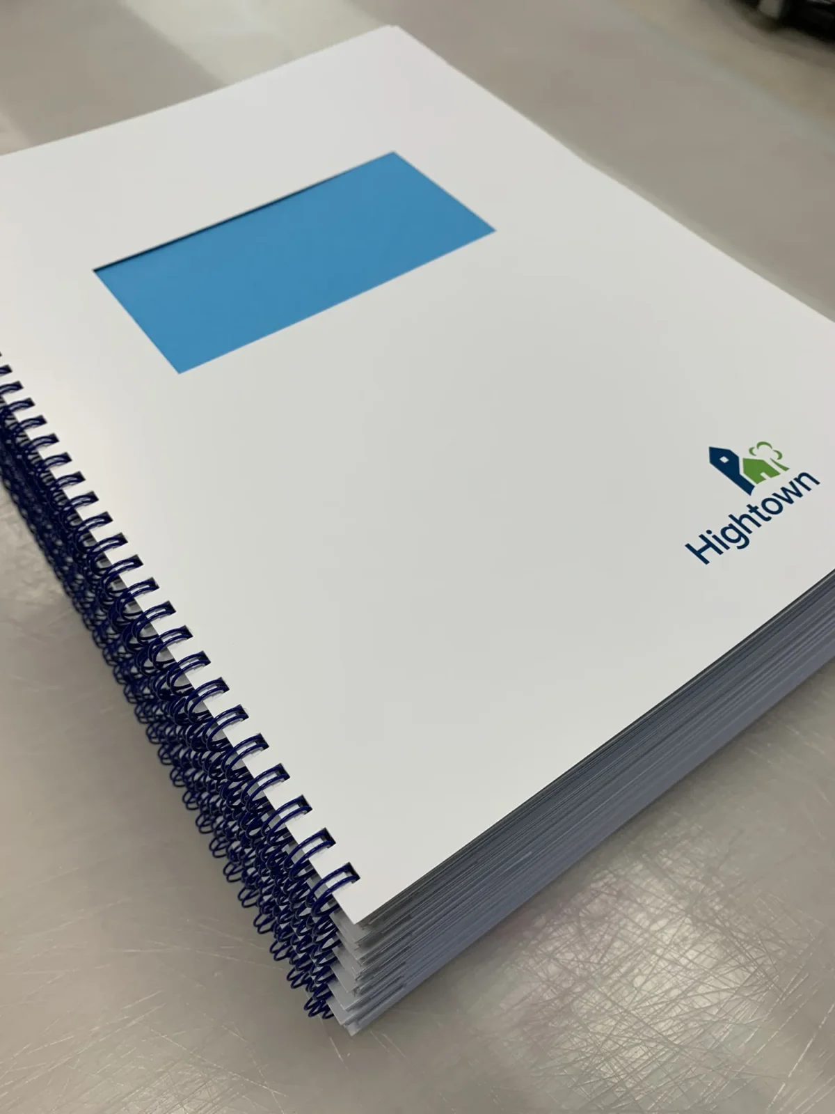 Stack of Hightown-branded spiral-bound booklets on metal surface
