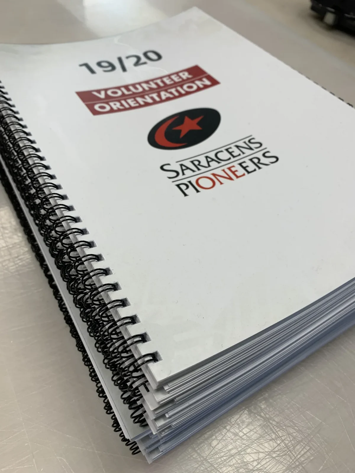 Stack of Saracens Pioneers volunteer orientation booklets