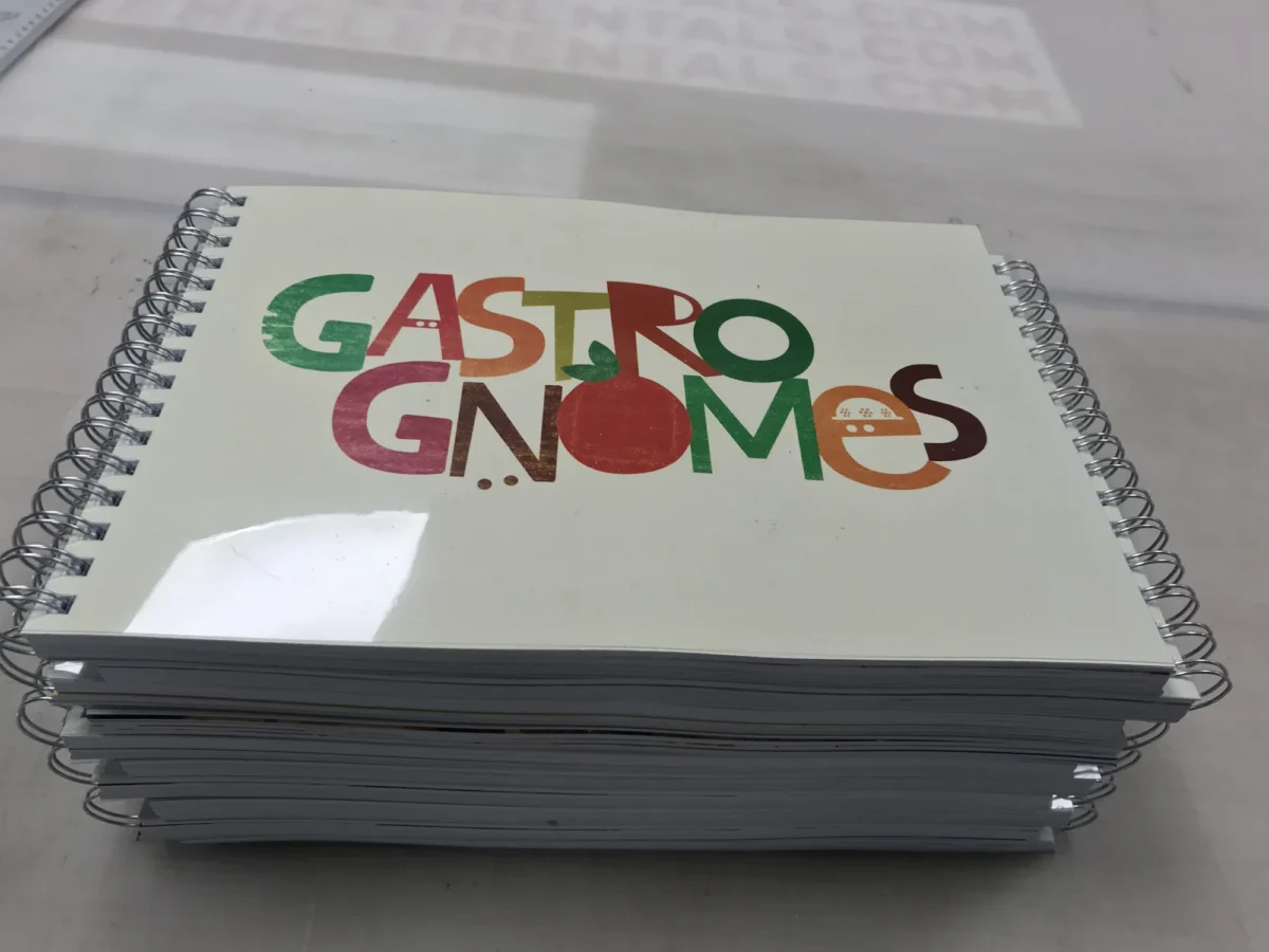 Stack of spiral-bound notebooks with colourful Gastromomes logo