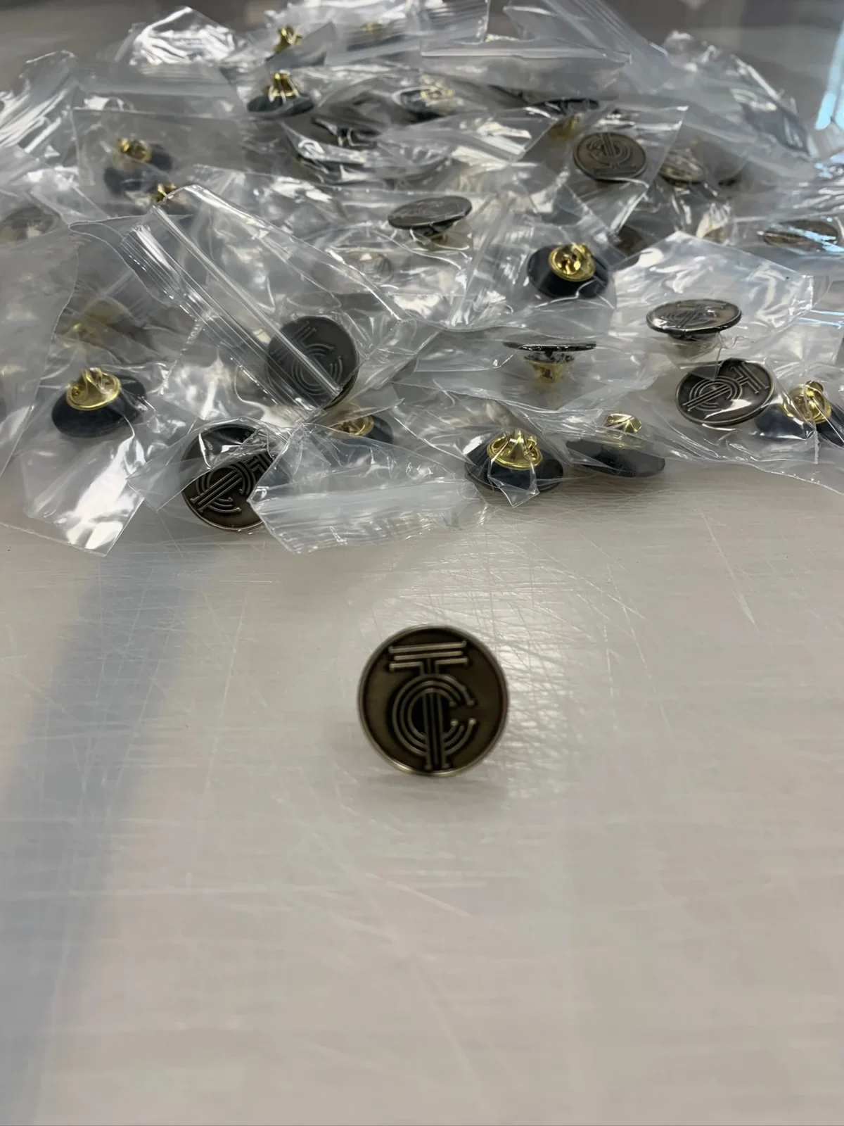 Black logo lapel pins in clear plastic bags