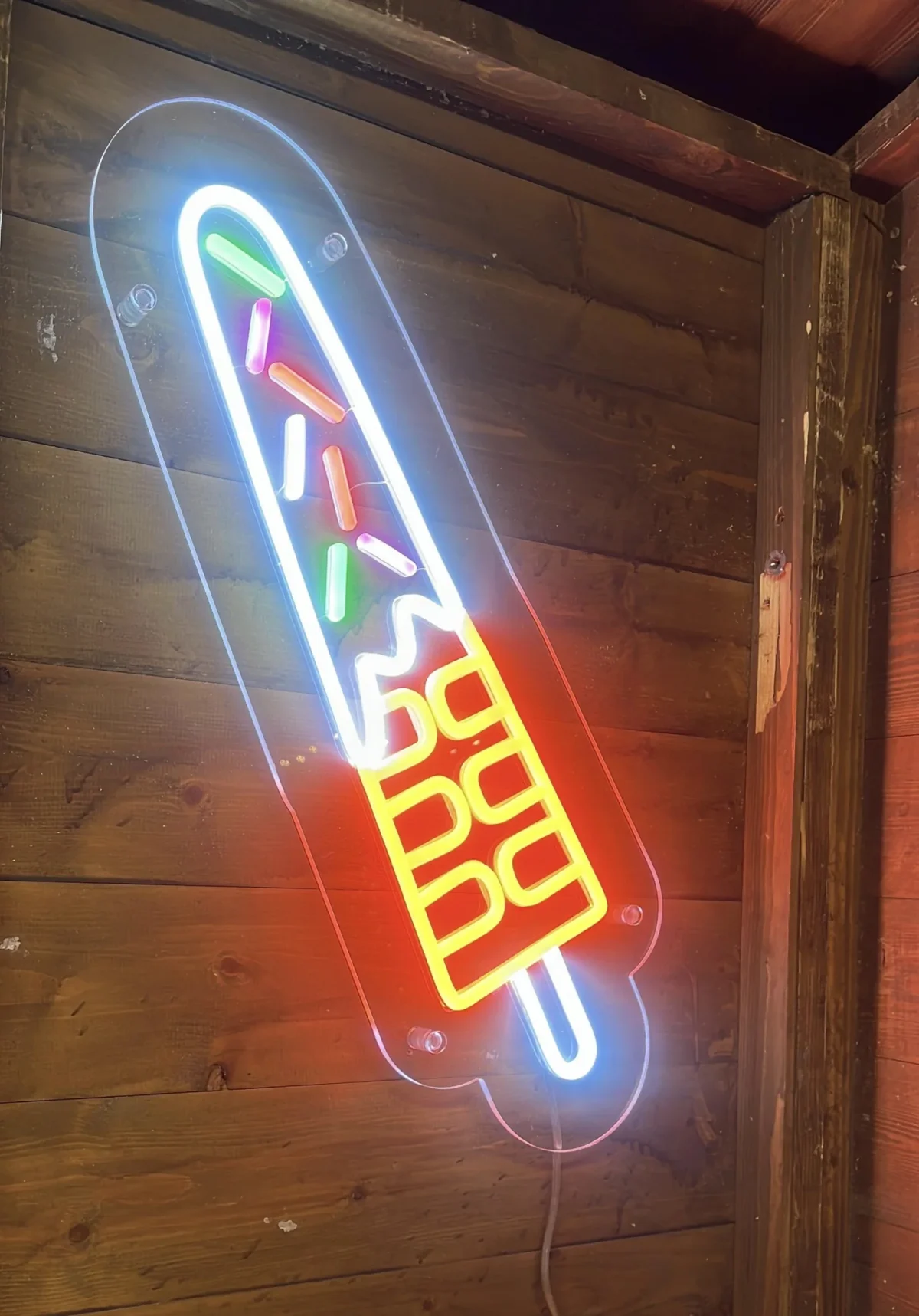 Colourful neon surfboard sign on a wooden wall