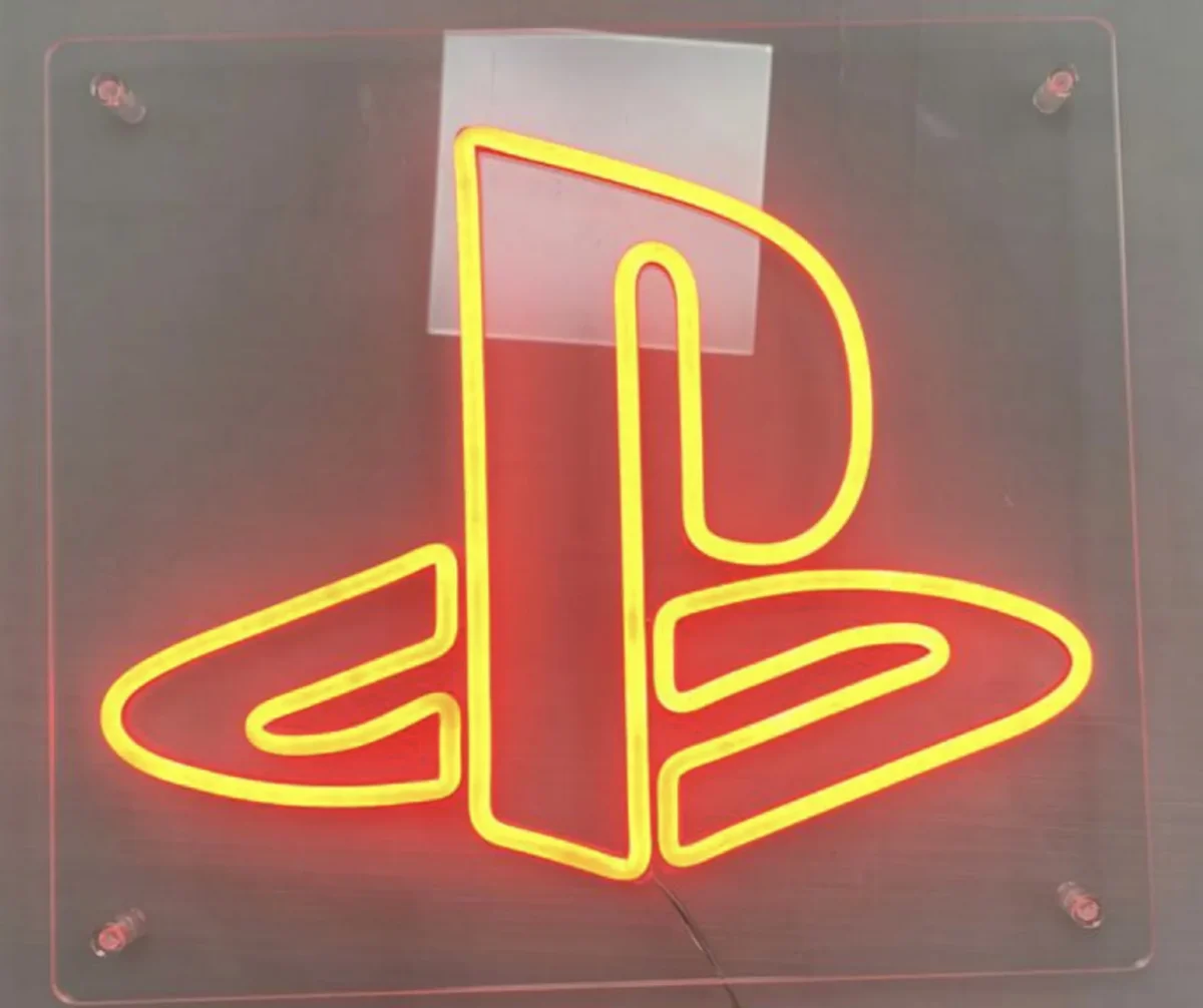 Illuminated yellow PlayStation logo on a dark wall