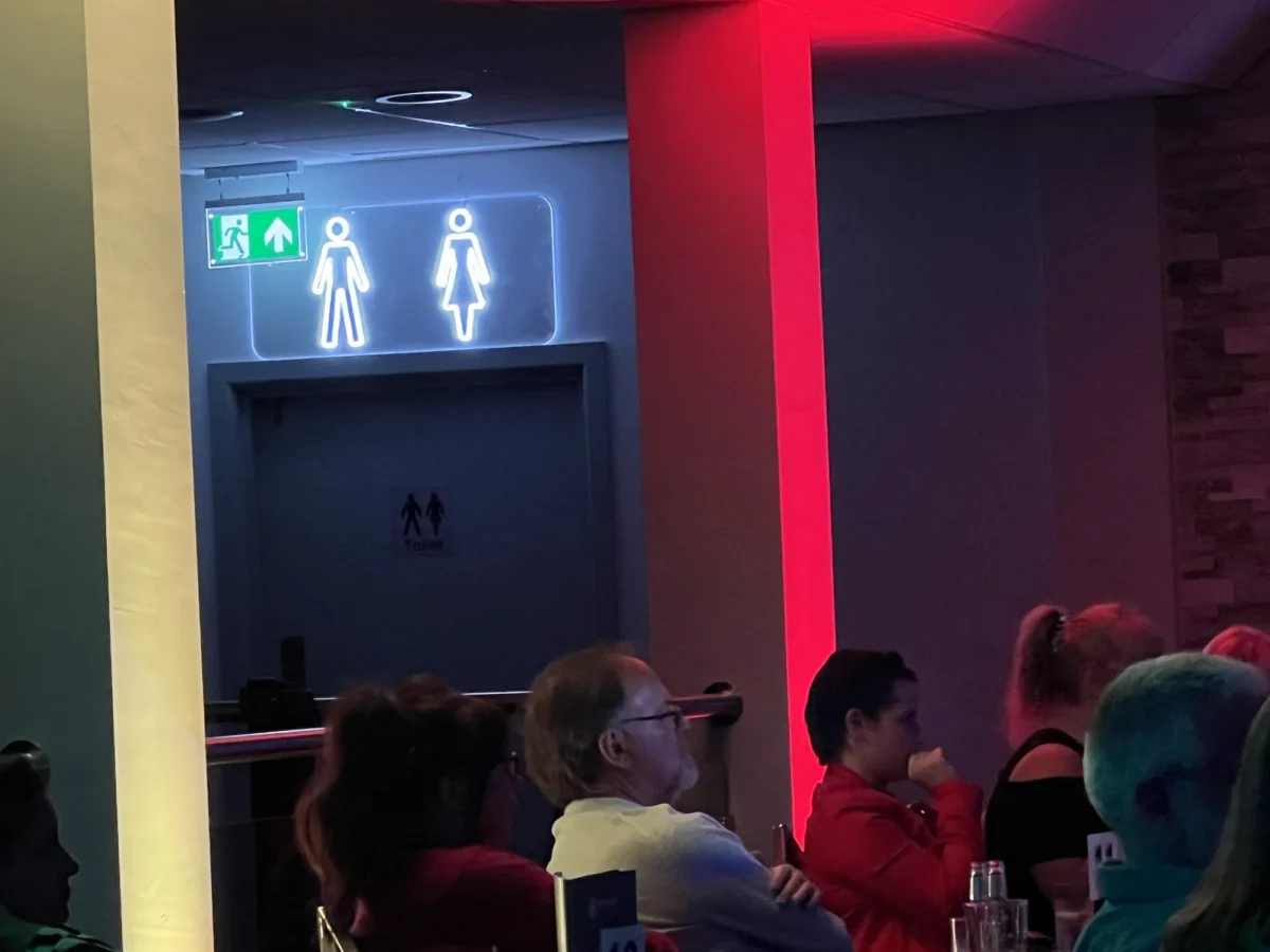Illuminated unisex toilet sign above doorway in restaurant