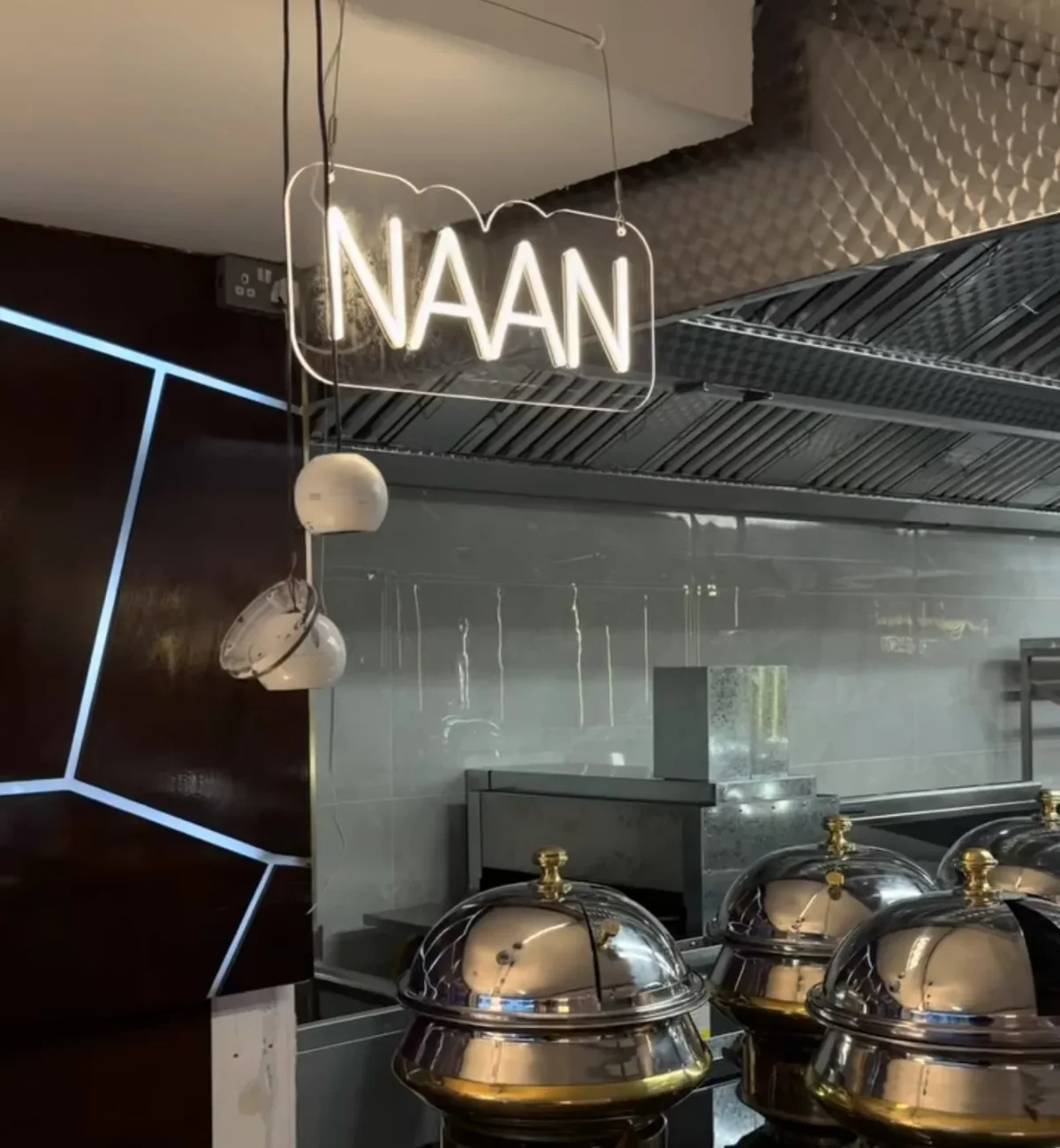 Illuminated NAAN sign above covered serving dishes