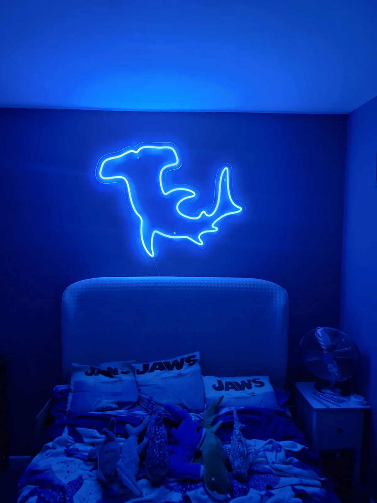 Blue neon shark sign above bed with shark toys