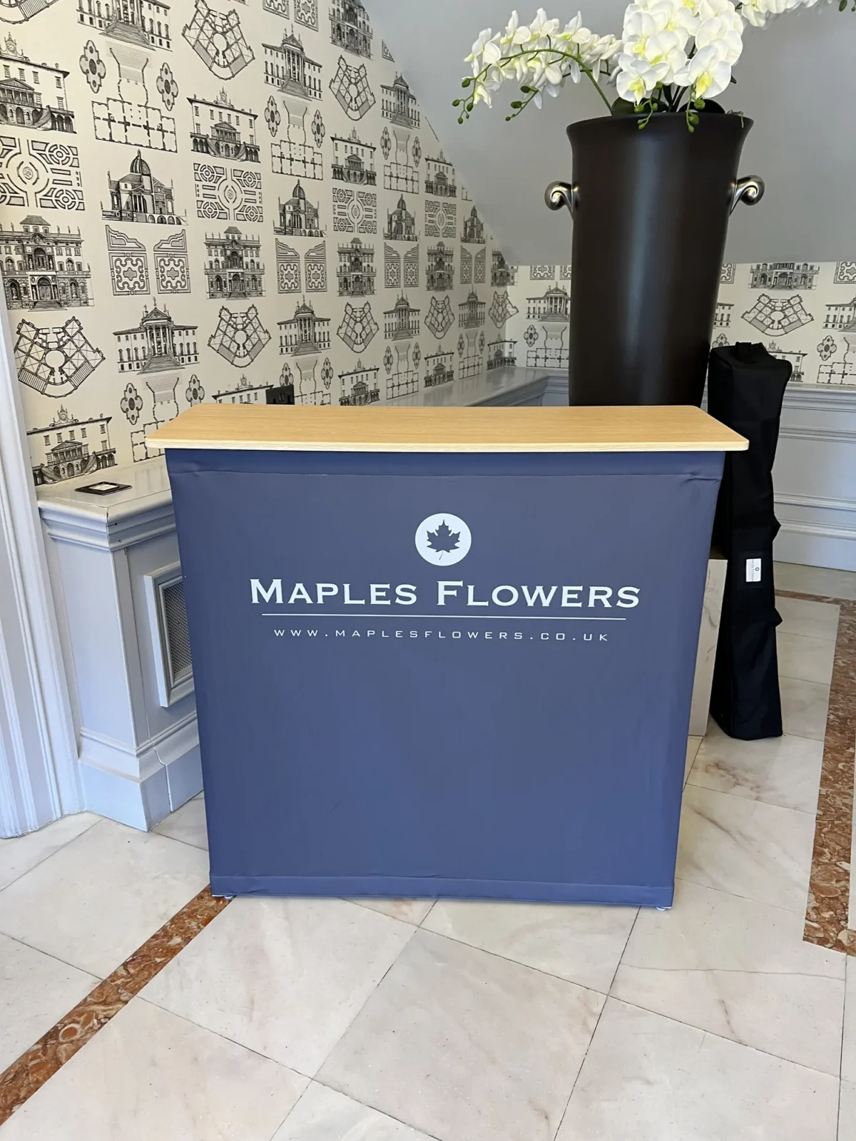 Maples Flowers counter with white orchids in black vase