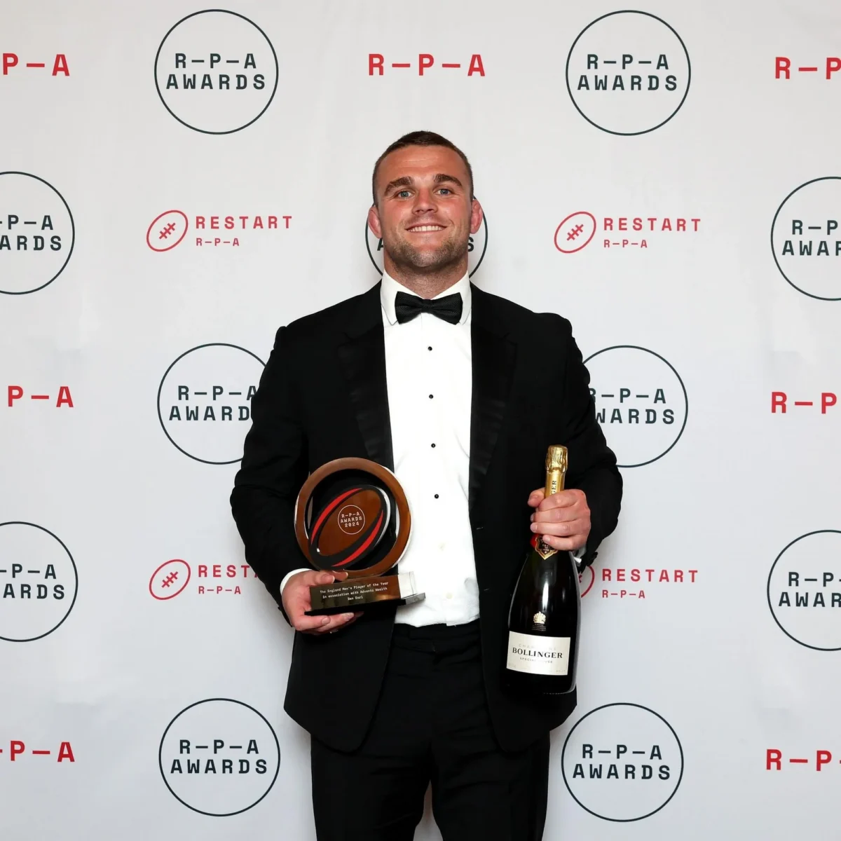 Man holds RPA award trophy and champagne bottle