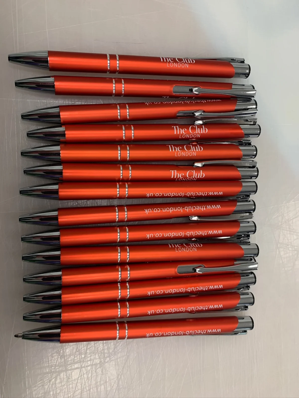 Stack of red branded The Club London ballpoint pens