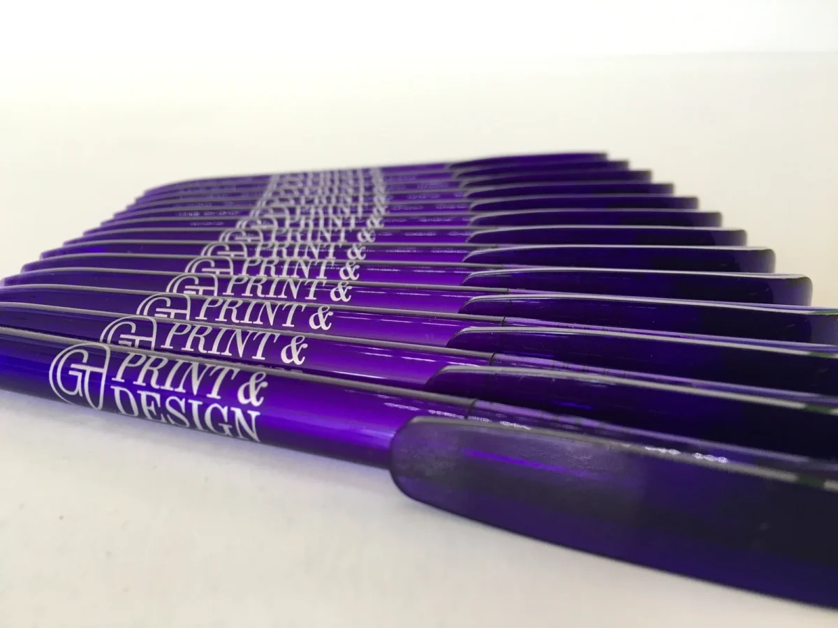 Rows of purple Print & Design branded pens