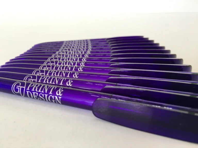 Rows of purple Print & Design branded pens