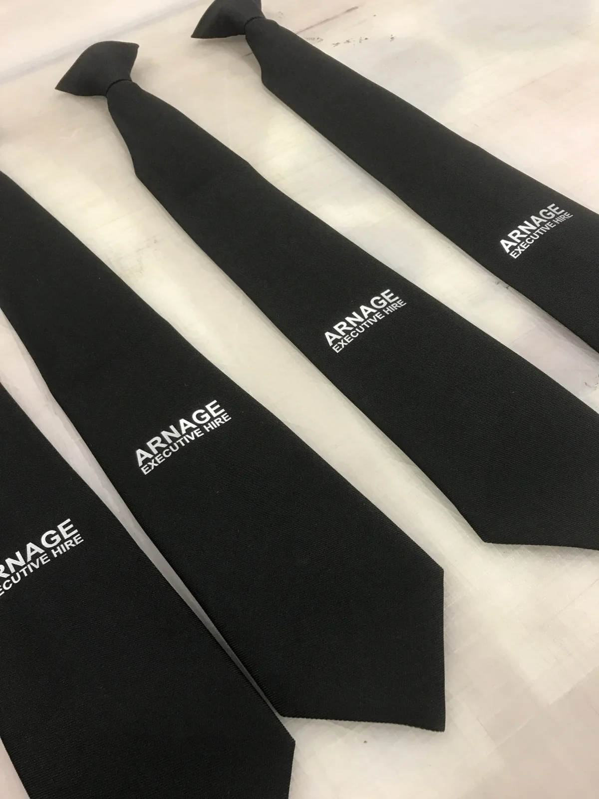 Black branded executive hire ties arranged on a table