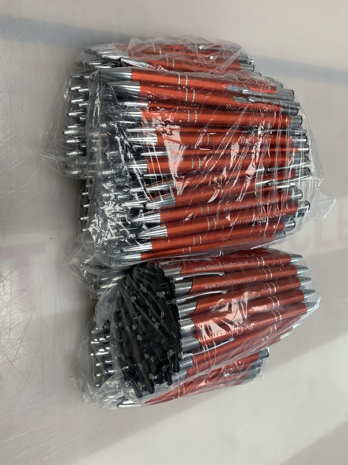 Bags of red branded pens stacked in a container