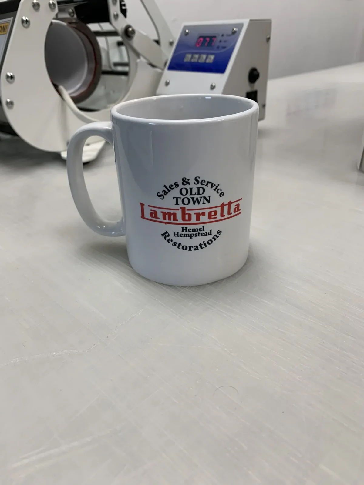 Lambretta restoration branded mug beside printing machine