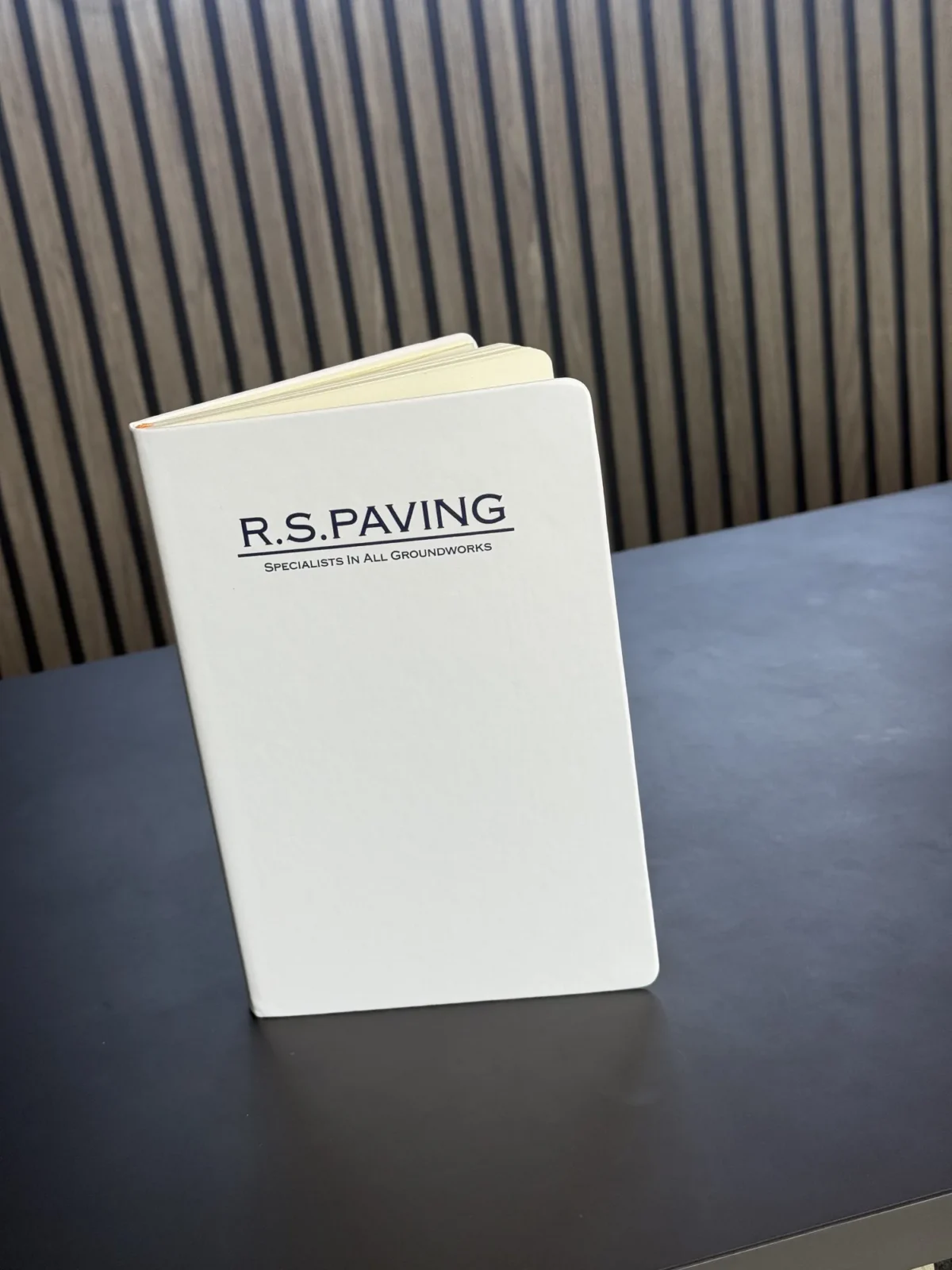 R.S. Paving branded notebook on a dark desk