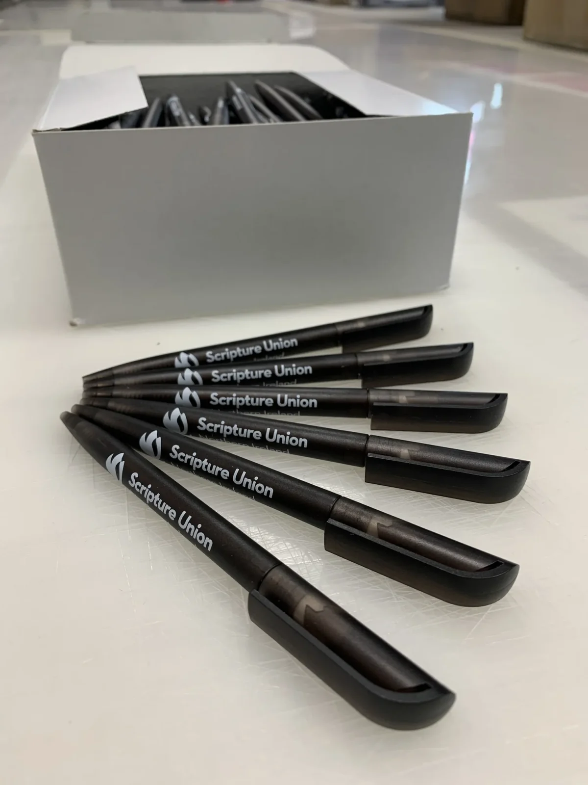 Branded black Scripture Union pens beside an open box