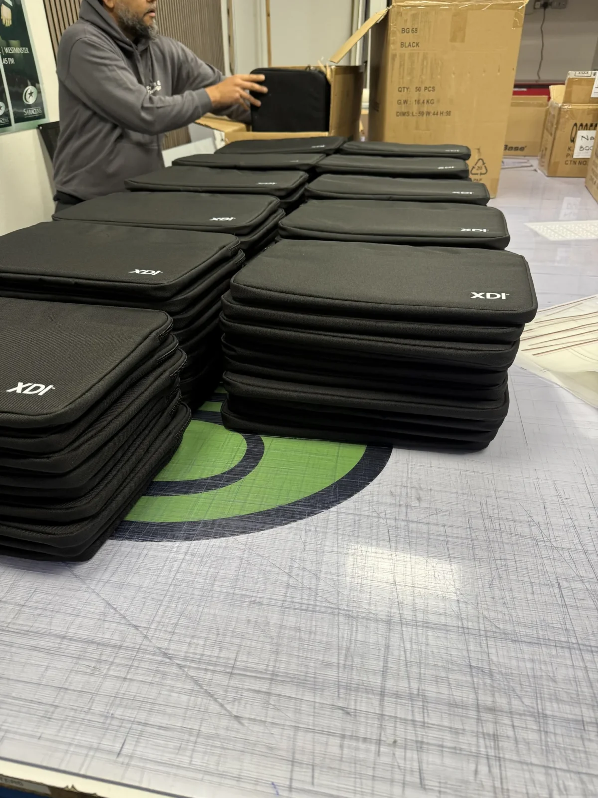 Worker packing stacks of black XDI laptop sleeves