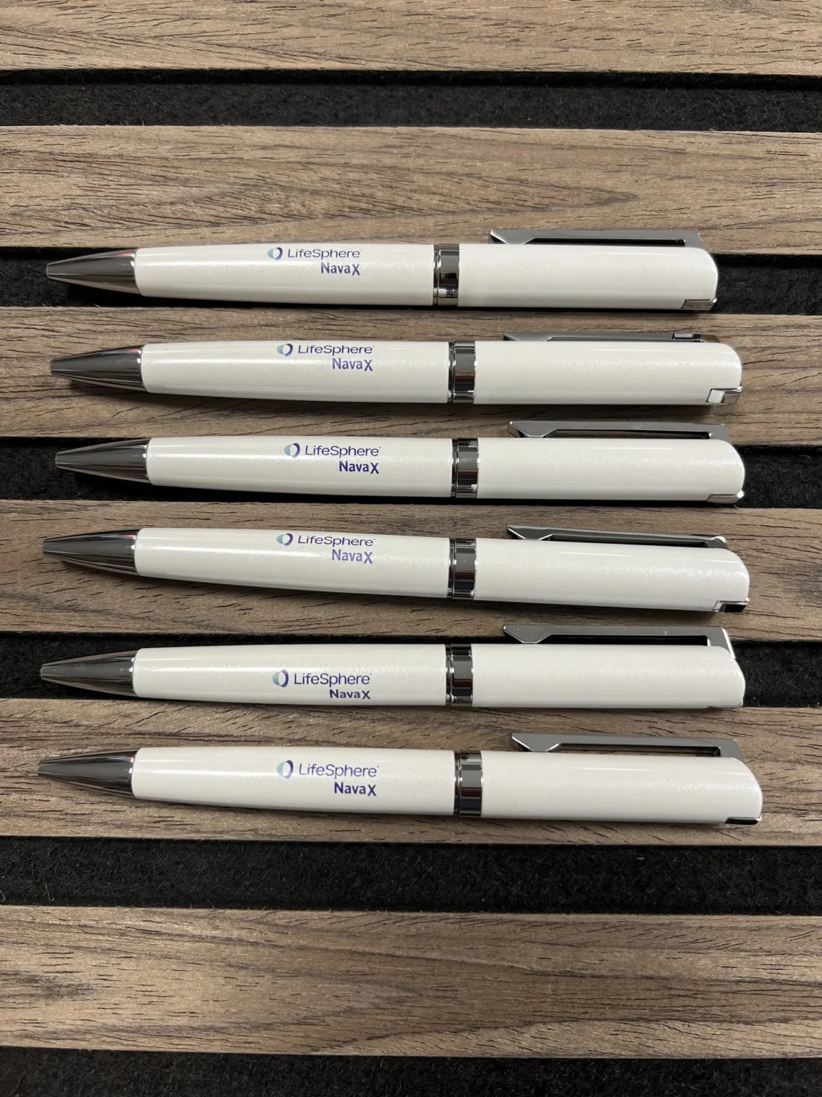 Six white LifeSphere NavaX branded pens on wooden slats