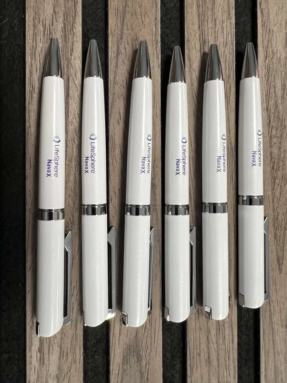 Six white LifeSphere NavaX pens on wooden slats