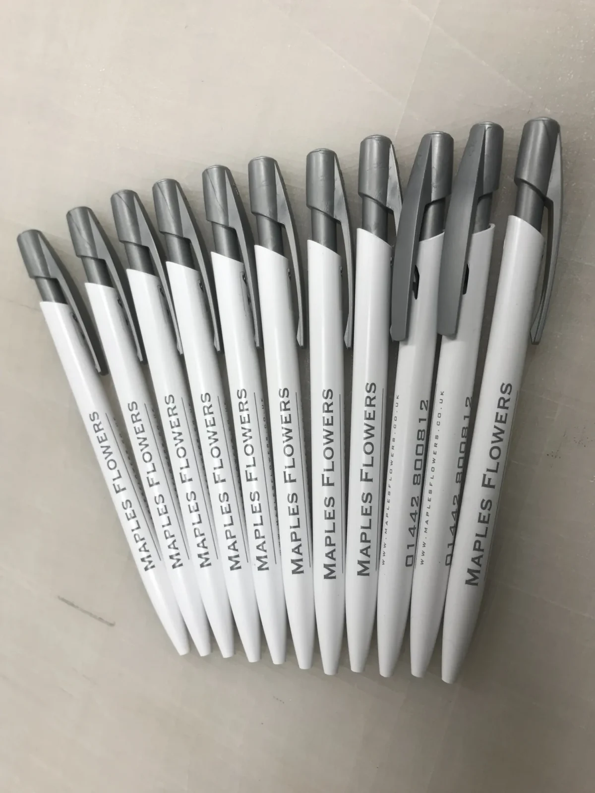 Branded white and black pens arranged in a fan