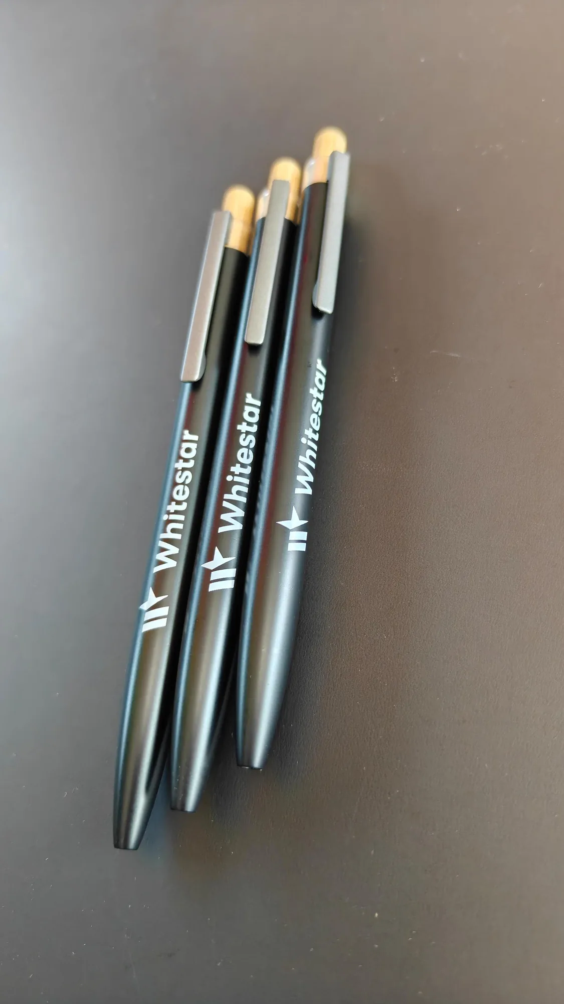 Three Whitestar black pens with silver clips on table