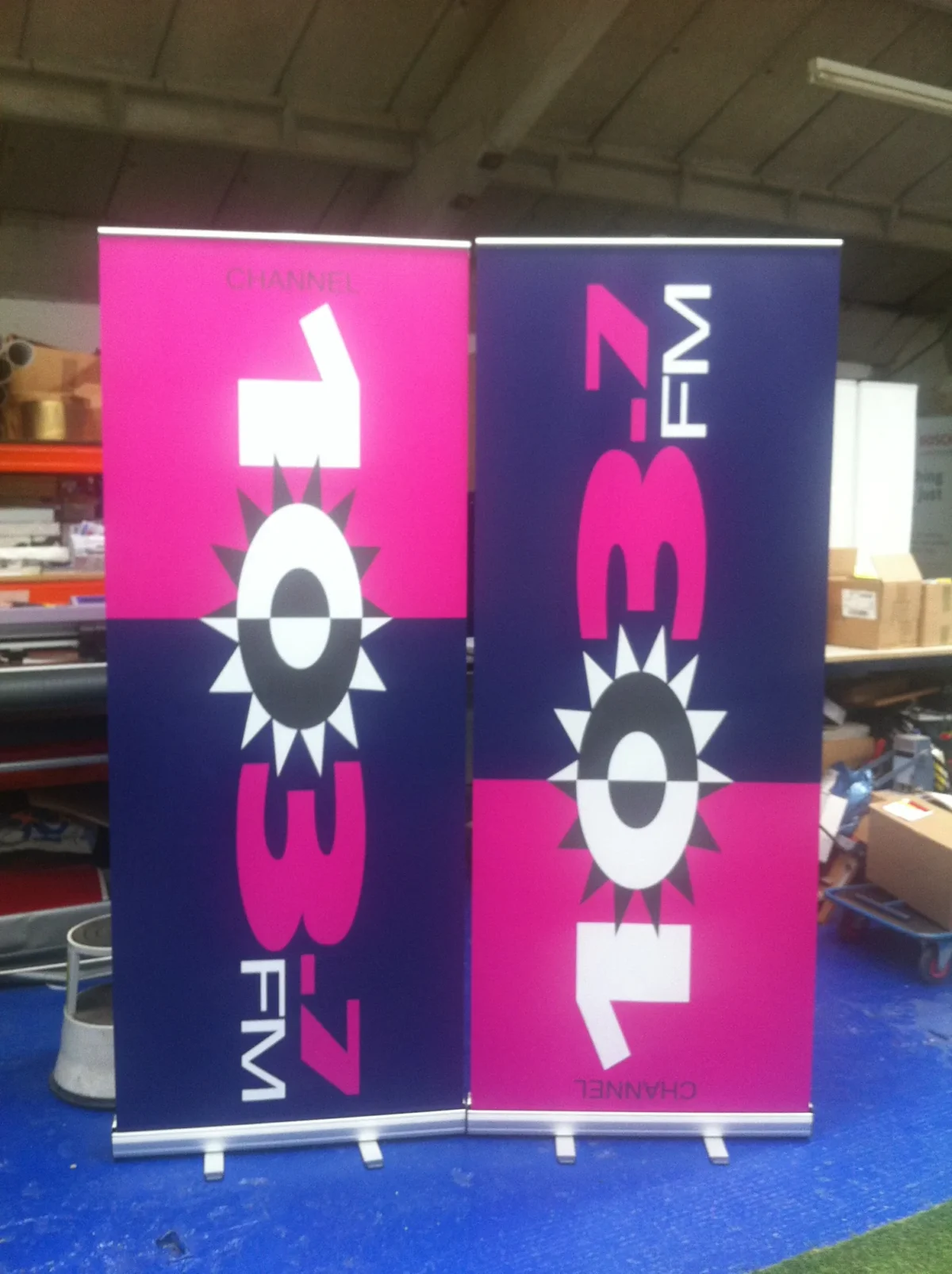 Two pink and navy Channel FM promotional banners