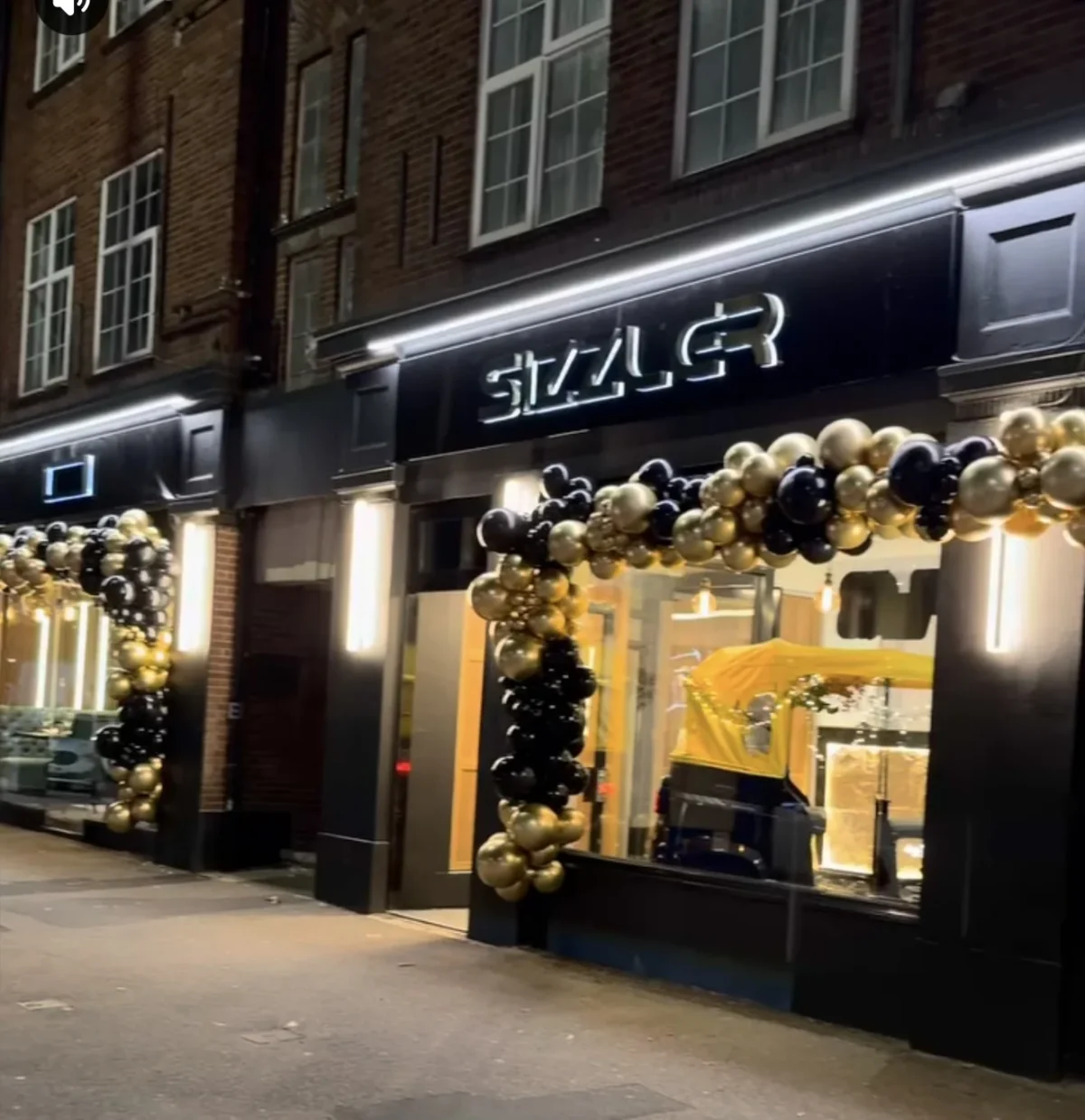 Stylish shopfront decorated with black and gold balloon garlands