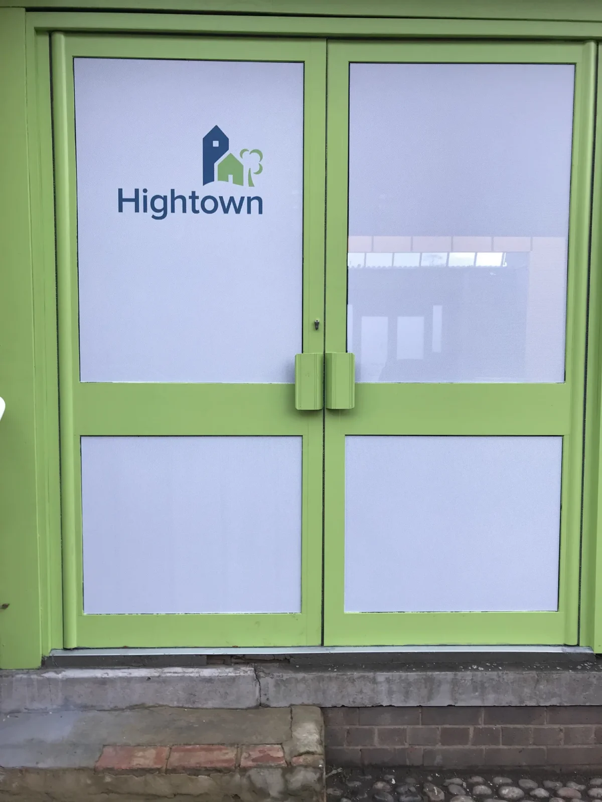 Green double doors displaying the Hightown housing logo