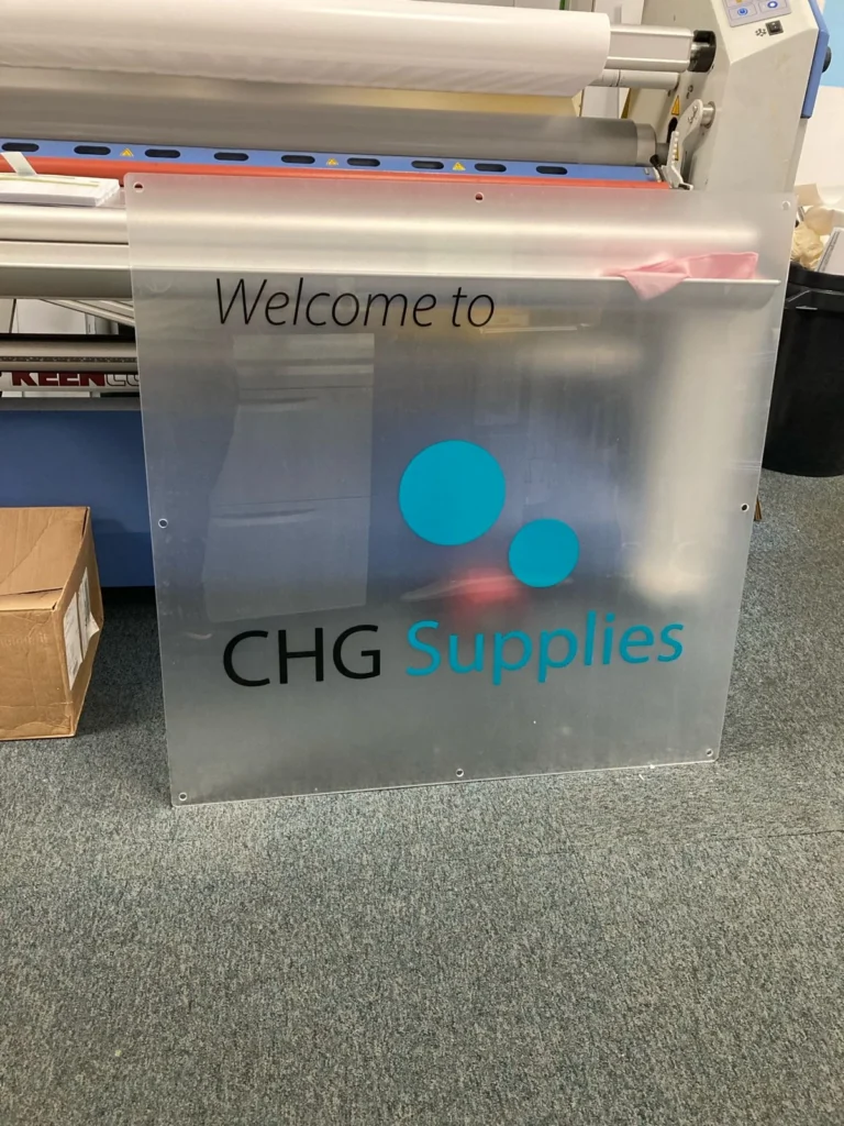 Frosted CHG Supplies welcome sign beside printing machine