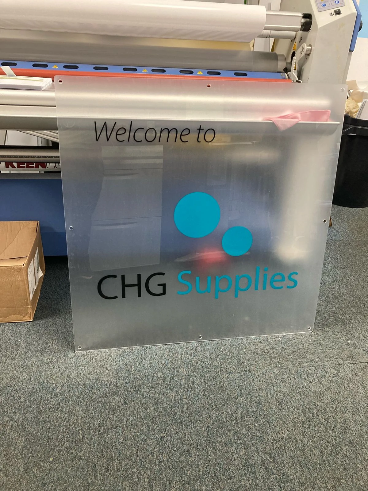 Frosted CHG Supplies welcome sign beside printing machine