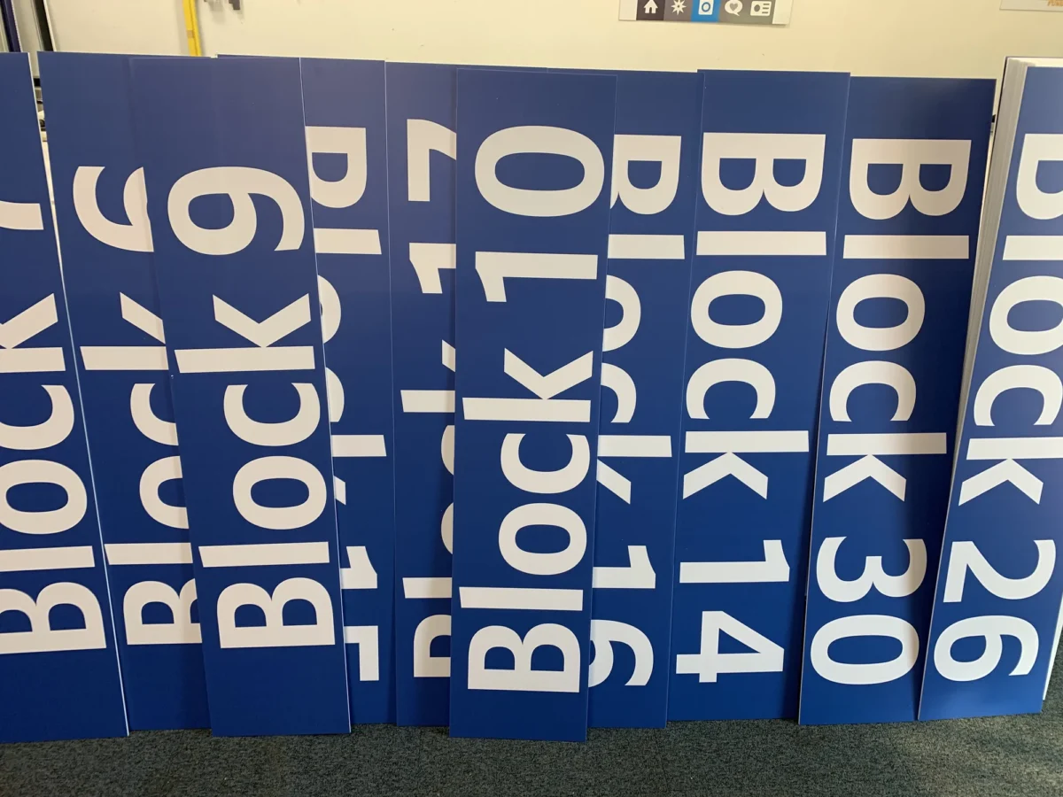 Blue wayfinding signs with white letters, numbers and arrows