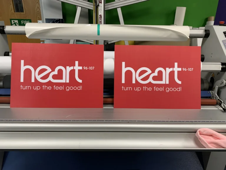 Two red Heart 96–107 signs beside laminating machine