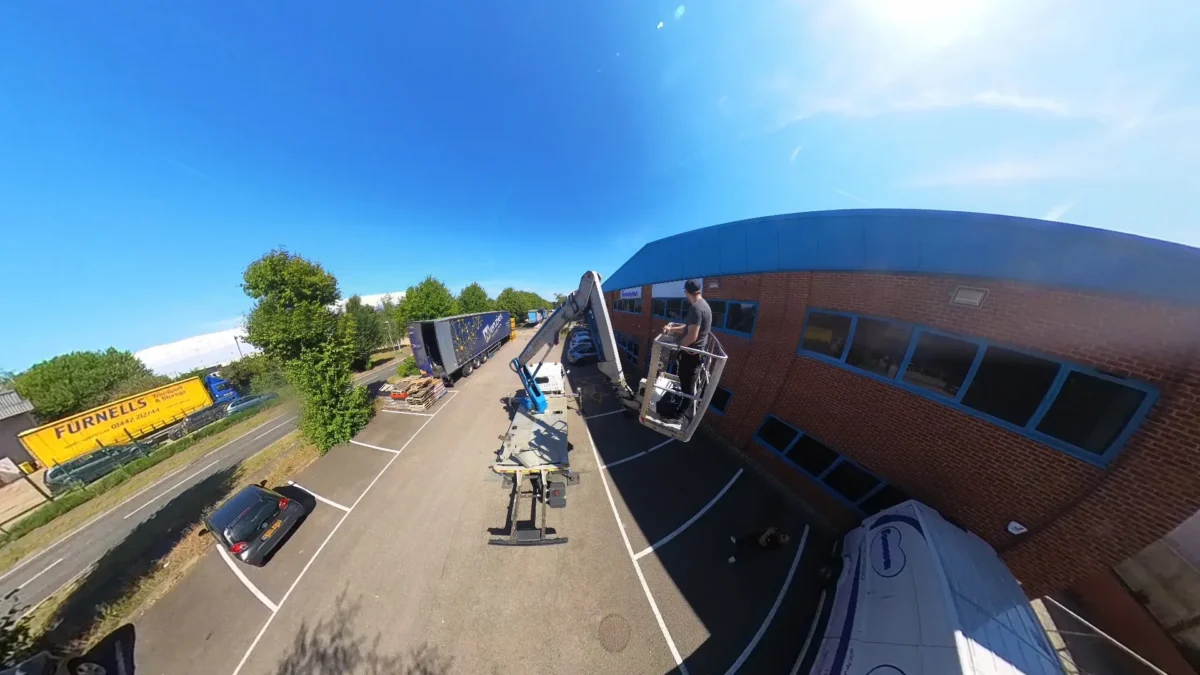 Worker in cherry picker beside brick industrial building